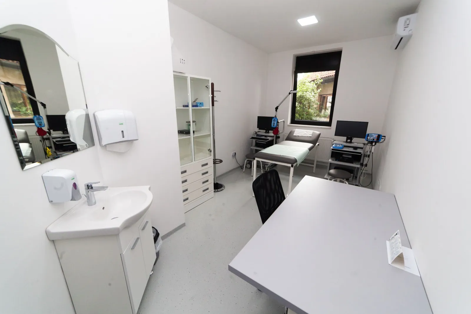 Heller Behandlungsraum einer Arztpraxis mit Waschbecken und Liege