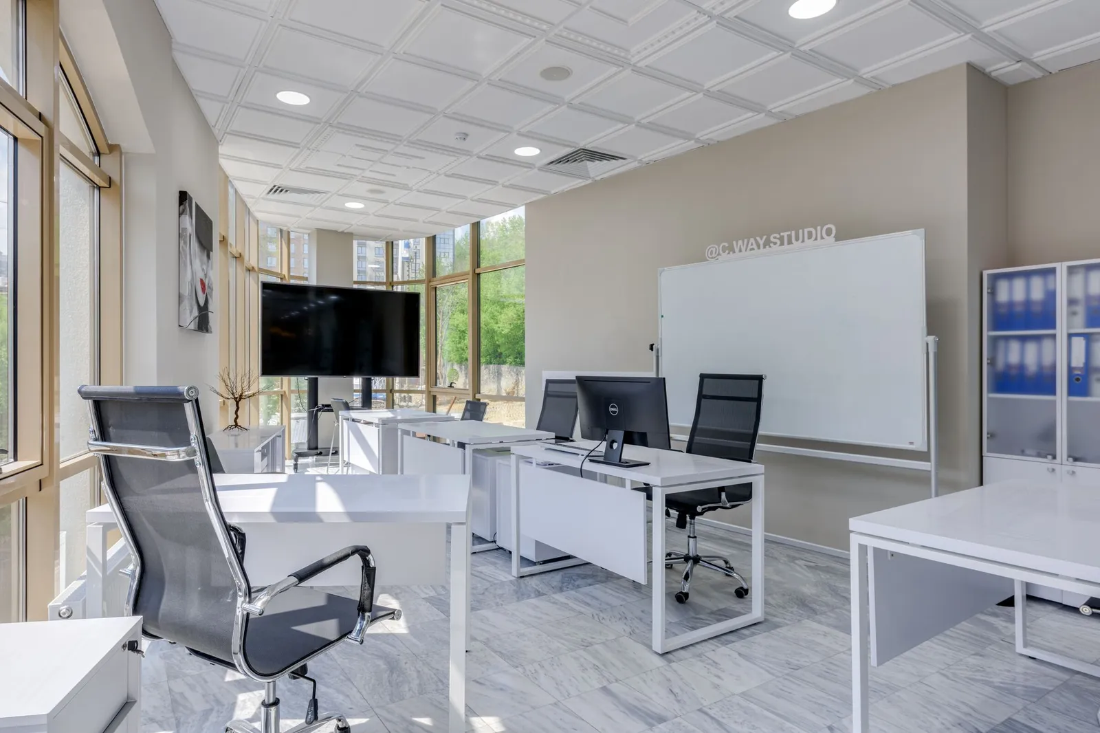 Helles Büro mit Schreibtischen, Bürostühlen und Whiteboard