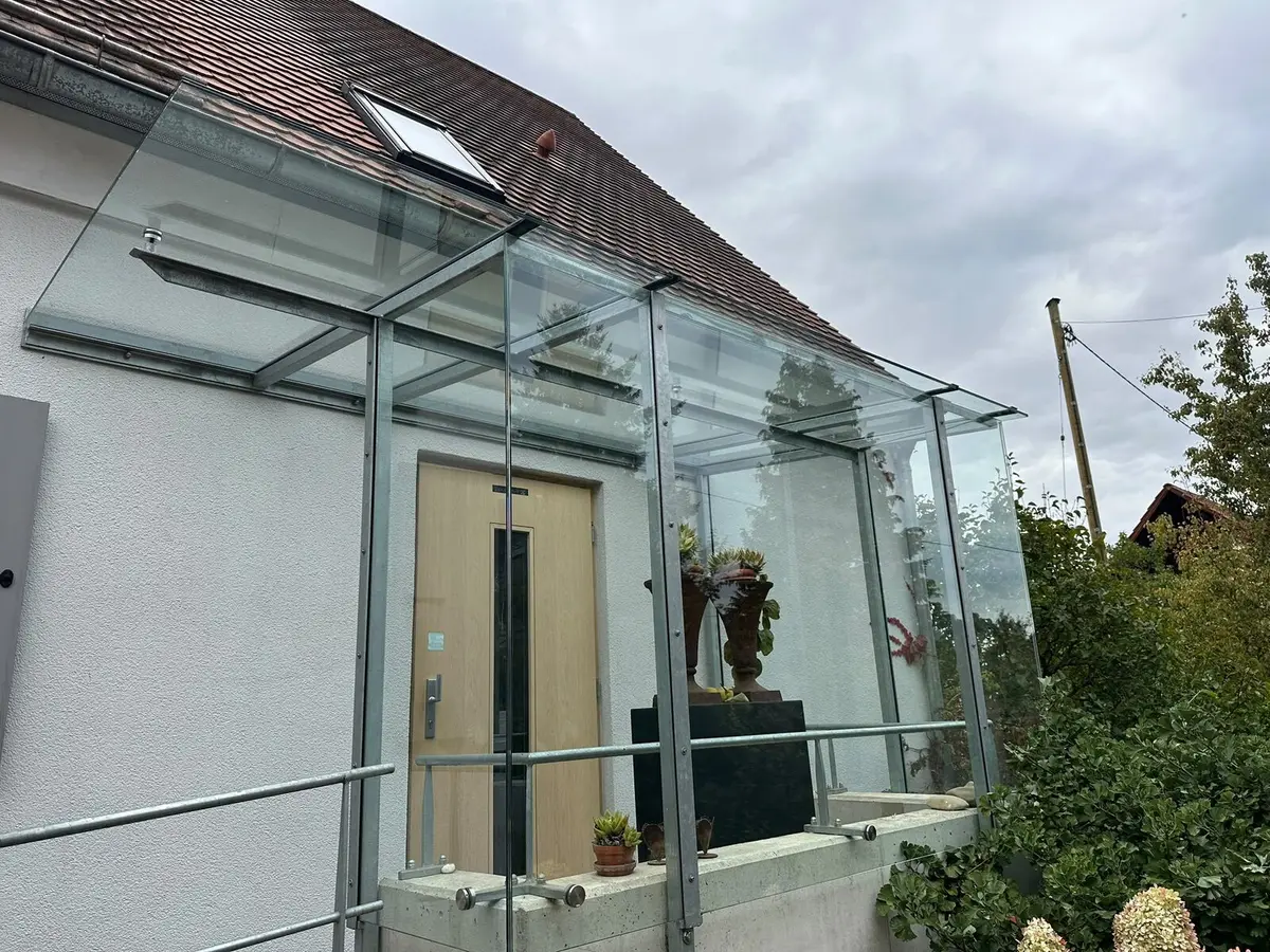 Klares Glasvordach mit Seitenwänden über dem Hauseingang nach der Reinigung